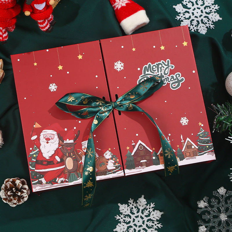 Red Christmas gift box with a festive design featuring Santa, reindeer, and snowy cottages. Wrapped with a green-golden ribbon, surrounded by pine cones and snowflake decorations.