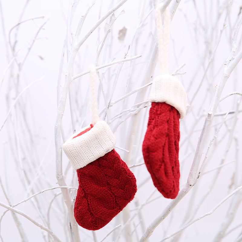 Red knitted mittens with white cuffs hang on white branches, creating a festive and cozy winter scene. The mittens add a pop of color against the neutral background.