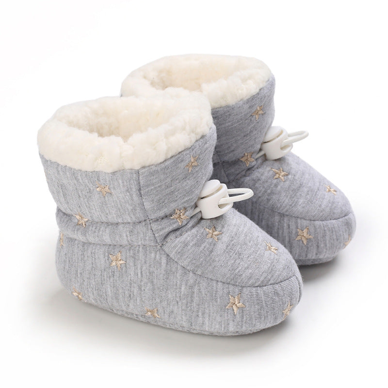 Gray baby booties with soft white lining, decorated with small gold stars. They have adjustable toggle closures and a cozy, plush texture, ideal for keeping little feet warm.