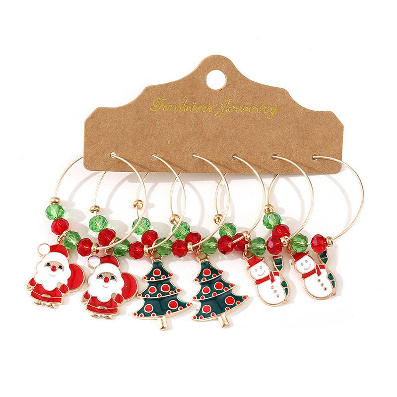 Set of six Christmas-themed wine charms featuring Santa, snowmen, and Christmas trees, adorned with red and green beads, displayed on a brown card labeled "Fashion Jewelry."