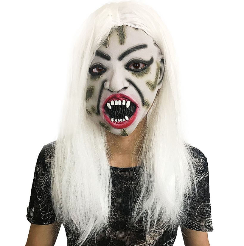 Person wearing a horror mask with sharp teeth, angry expression, and long white hair, dressed in a dark, patterned shirt.