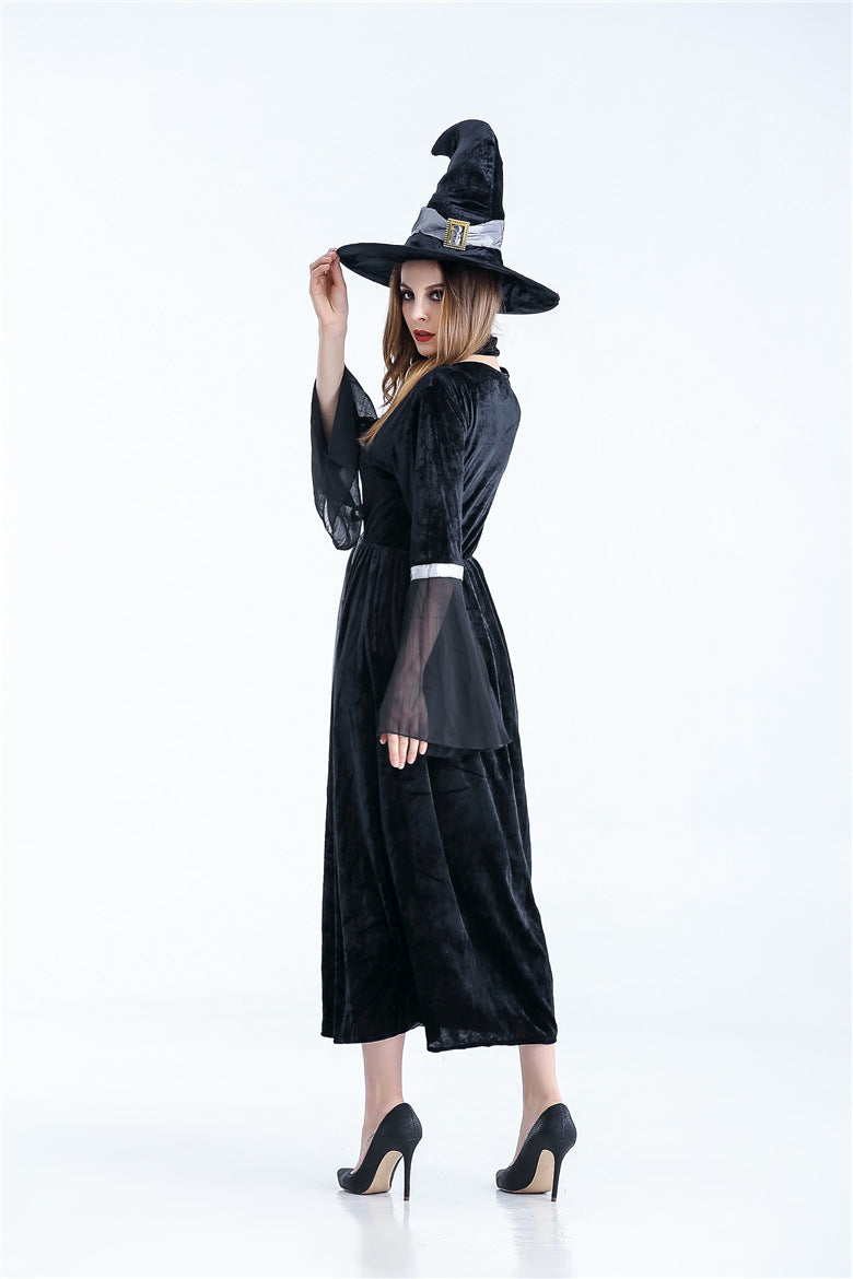 A woman in a black witch costume poses sideways, wearing a pointed hat. She stands confidently in black high heels against a plain white background.