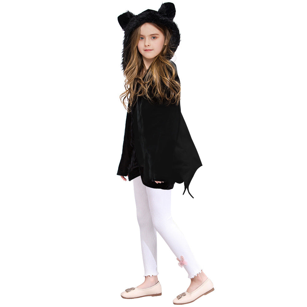 Young girl in a black hooded cape with ears, wearing white leggings with a pink embellishment and beige flats, stands against a plain white background.