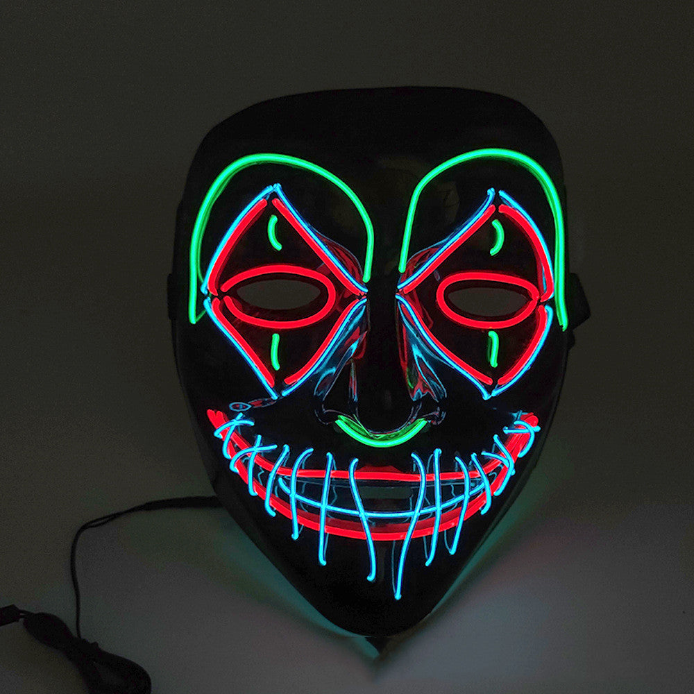 A black mask lit with neon outlines features a sinister smile and eyes. The neon colors include green, red, and blue, creating an eerie and vibrant effect.