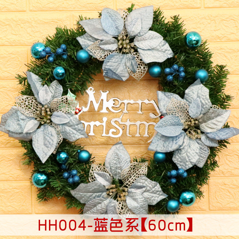 Christmas wreath with blue flowers and ornaments, featuring a "Merry Christmas" sign in the center. Set against a yellow brick wall, 60cm in diameter.