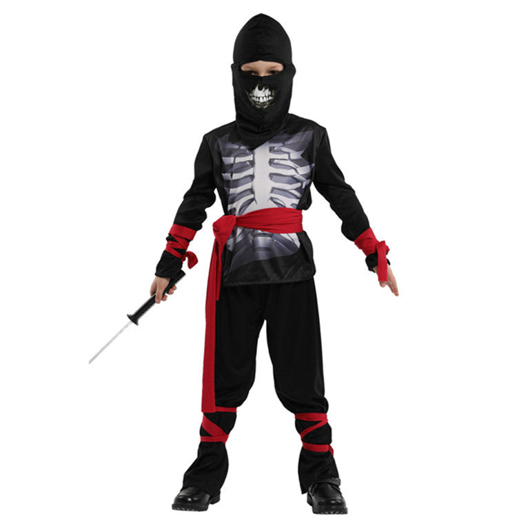 Child in a ninja costume featuring a skeleton design, black hood, red sash, and red wrist and ankle ties, holding a toy sword. The mask has a sinister skull print.