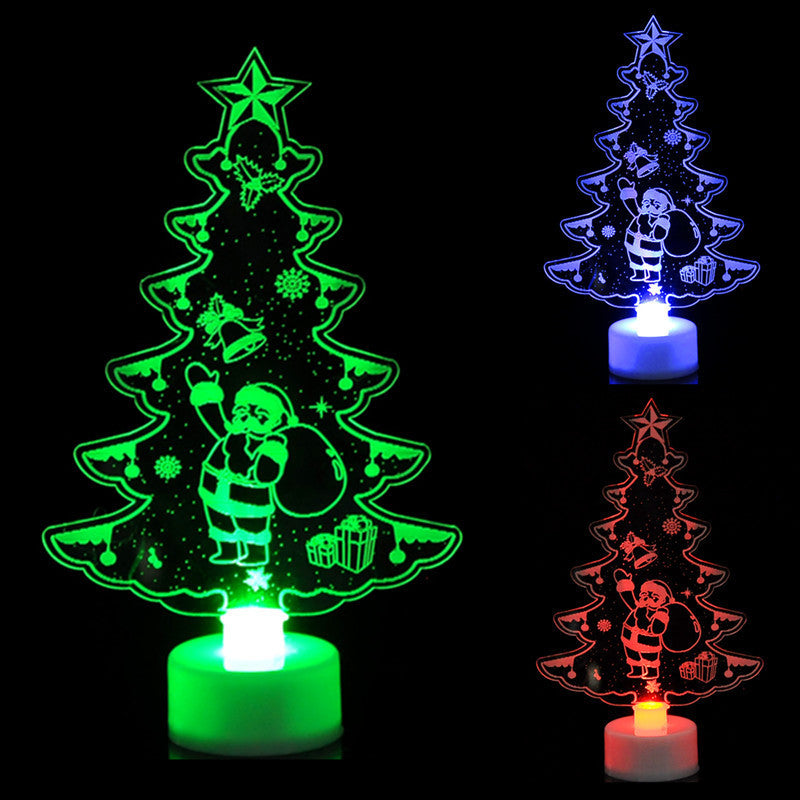 Three glowing acrylic Christmas trees feature Santa, bells, and gifts. The trees are lit in green, blue, and red, each with a star on top and snowflakes surrounding.