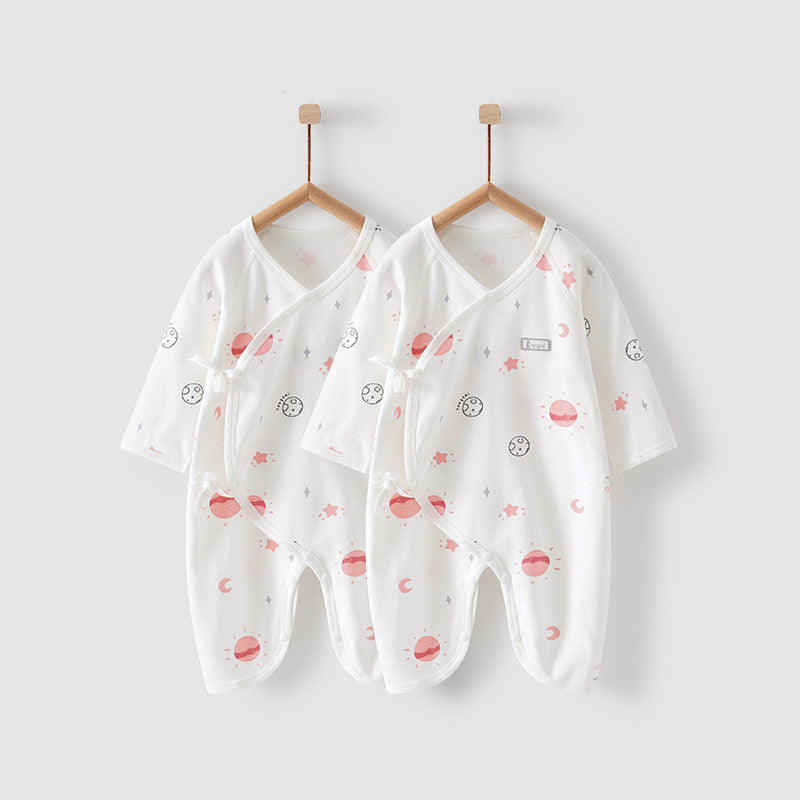 Two white baby onesies with pink and grey cartoon space-themed prints, including planets and stars, hang on wooden hangers against a light gray background.