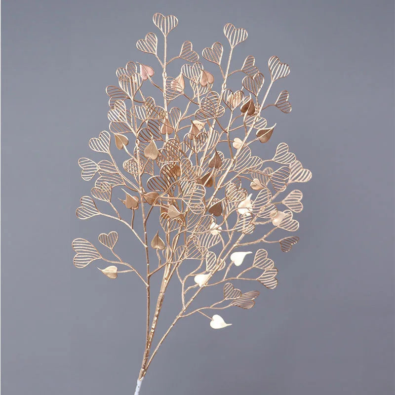Golden branches with heart-shaped leaves intricately patterned, arranged against a soft gray background, creating an elegant, decorative floral design.