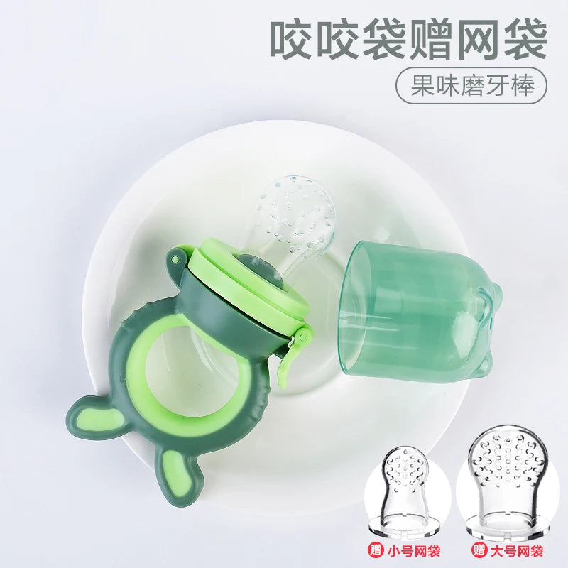 Green baby teething feeder with a ring handle, sitting on a white plate next to a transparent green cap. Two additional silicone feeder attachments are displayed below.
