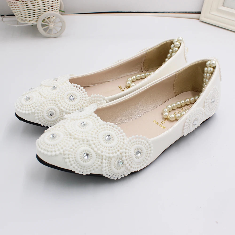 Elegant white ballet flats adorned with pearl and rhinestone embellishments in a floral pattern, featuring a pearl accent around the heel.