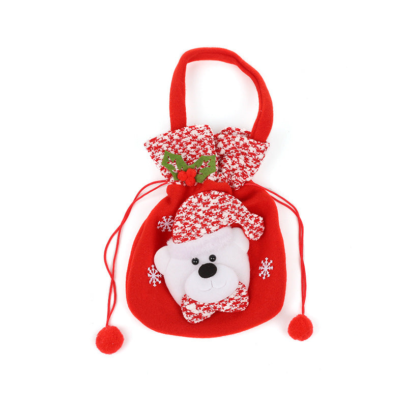 Red holiday gift bag featuring a teddy bear wearing a red and white hat. Decorated with snowflakes and holly, the bag has a handle and drawstrings with pom-poms.