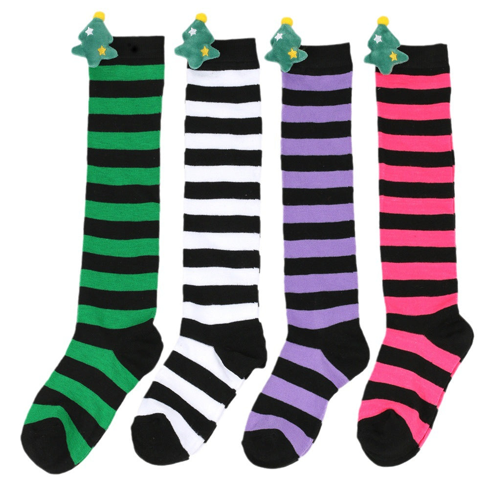 Four pairs of striped knee-high socks in green, white, purple, and pink, each with black stripes and adorned with a small Christmas tree decoration at the top.