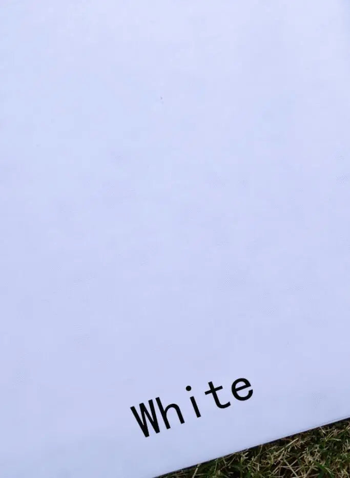 White canvas with the word "White" printed in black near the bottom right corner. The canvas is placed on grass, partially visible at the bottom edge.