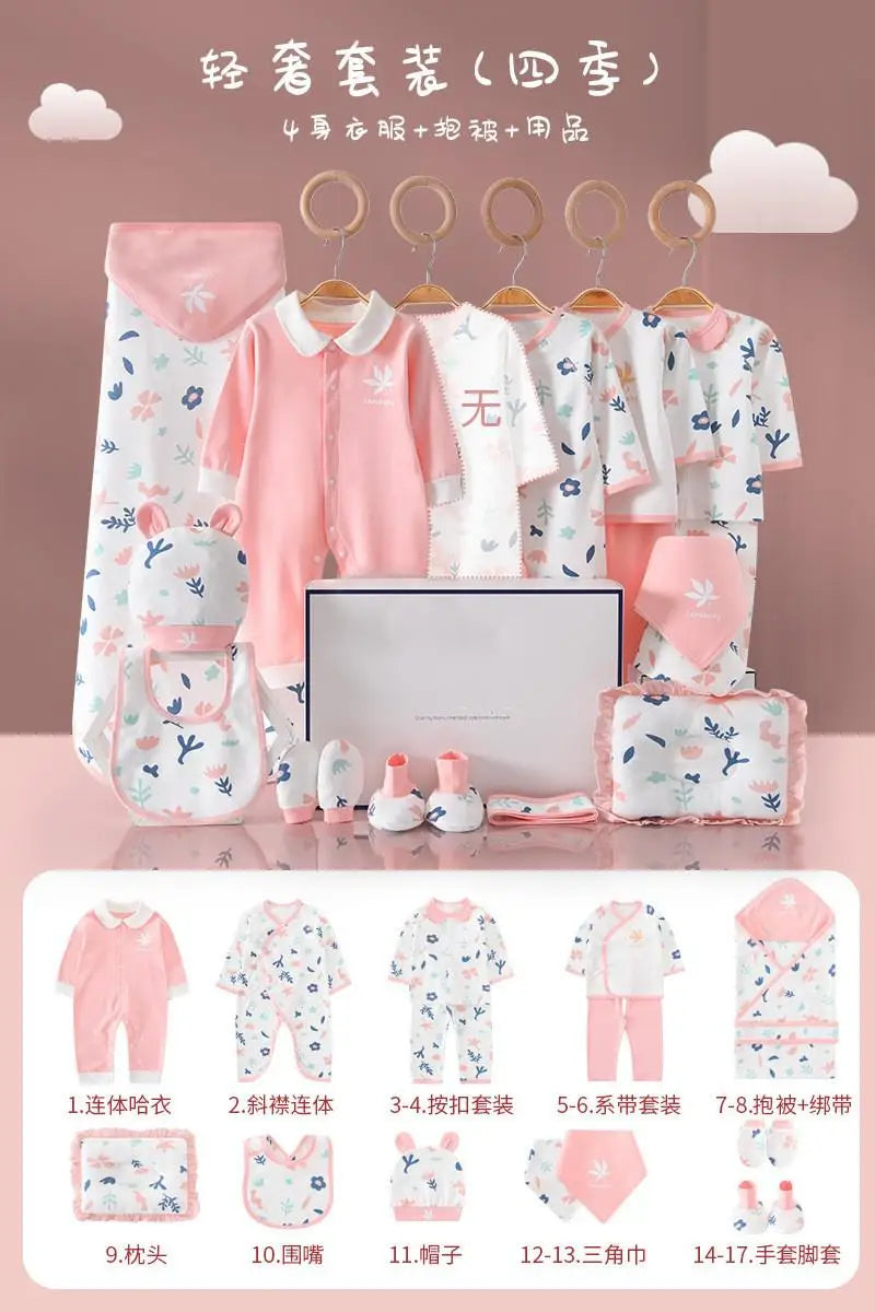 Baby clothing set in soft pinks and whites including onesies, bibs, hats, mittens, blanket, and gift box, all with cute floral and animal prints.