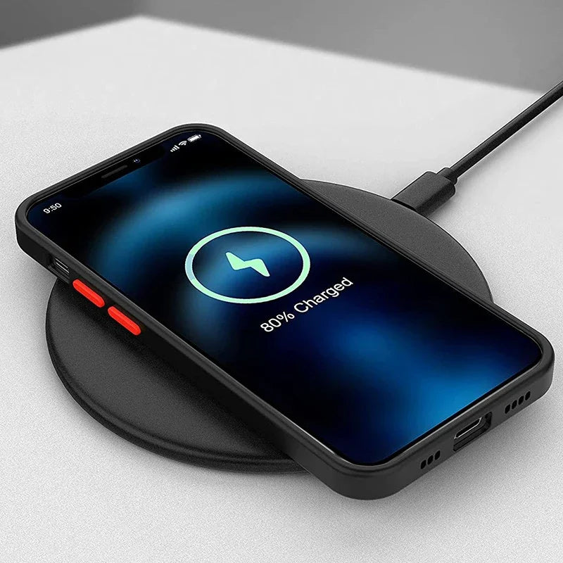 Smartphone on a wireless charging pad showing 80% charged. The screen displays a battery icon, and the device has red side buttons. The charger is on a light-colored surface.