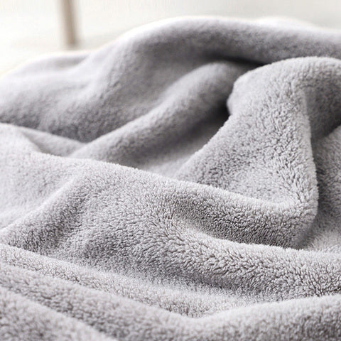 Close-up of a soft, gray fleece blanket with a fluffy texture. The fabric is gently folded, creating light and shadow contrasts that emphasize its plushness.