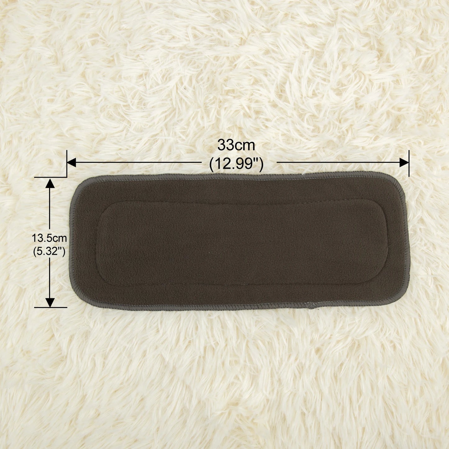 Dark gray rectangular pad measuring 33cm by 13.5cm placed on a fluffy white surface. Dimensions are labeled, indicating 12.99 inches by 5.32 inches.
