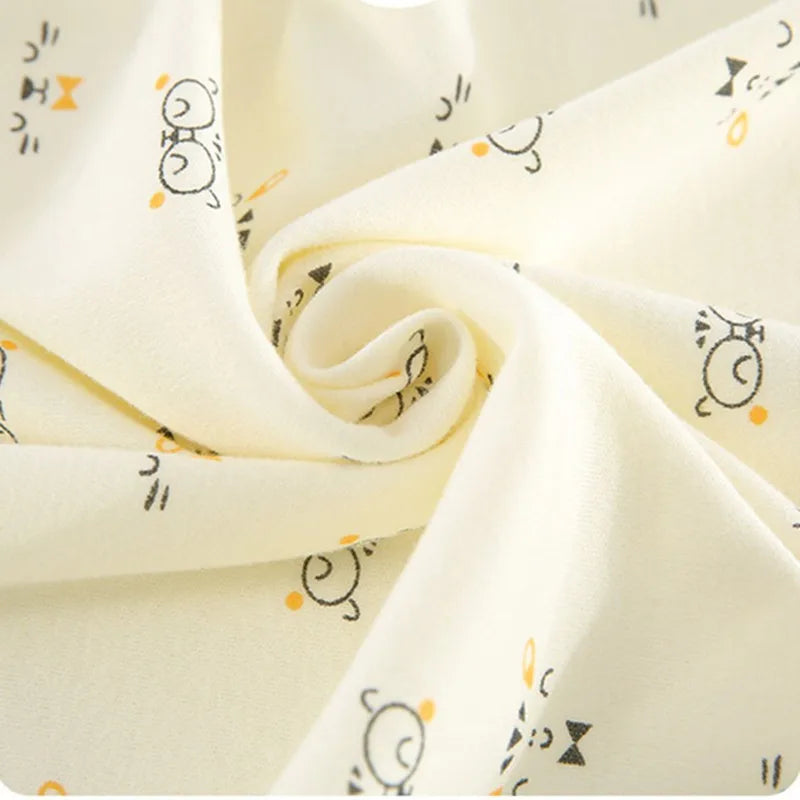 Cream fabric with a pattern of cute cartoon cat faces with orange and black accents, swirled elegantly in the image to show texture.