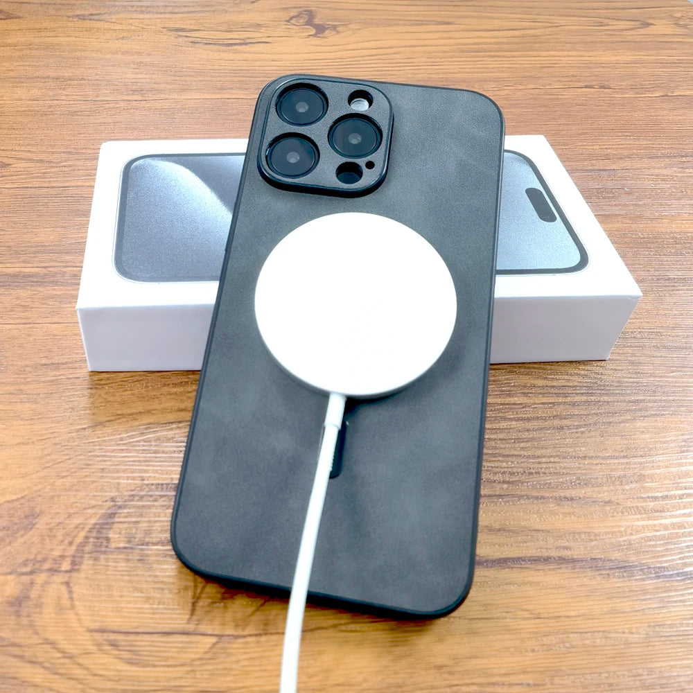 A smartphone with a black case is on a wooden table, connected to a white wireless charger. The phone is placed over its original packaging box.