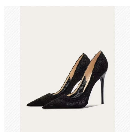 Black lace high heels with pointed toes and stiletto heels are displayed against a plain background. The shoes feature a scalloped edge for an elegant design.