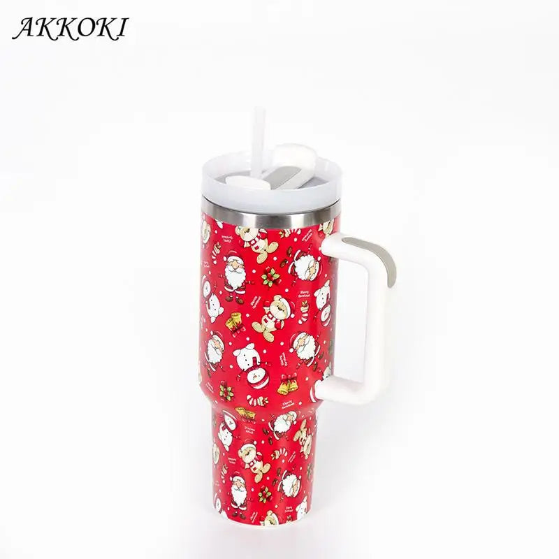 Red insulated travel mug with a straw and white handle, decorated with festive Christmas patterns, including snowmen, Santa Claus, and bells.