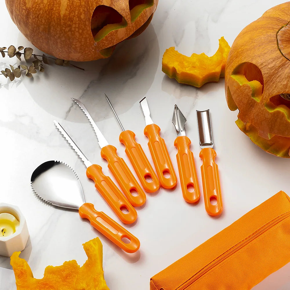 Pumpkin carving tools with orange handles are arranged on a white surface alongside carved pumpkins and pumpkin pieces. A small yellow candle and an orange bag are also visible.