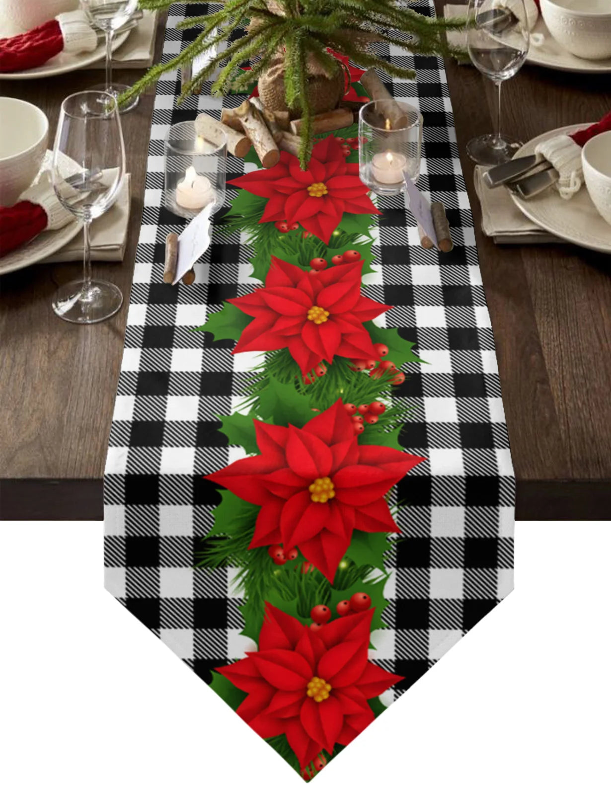 A festive table setting with a plaid runner featuring red poinsettias and greenery. Lit candles and dishware with red napkins complete the cozy holiday atmosphere.