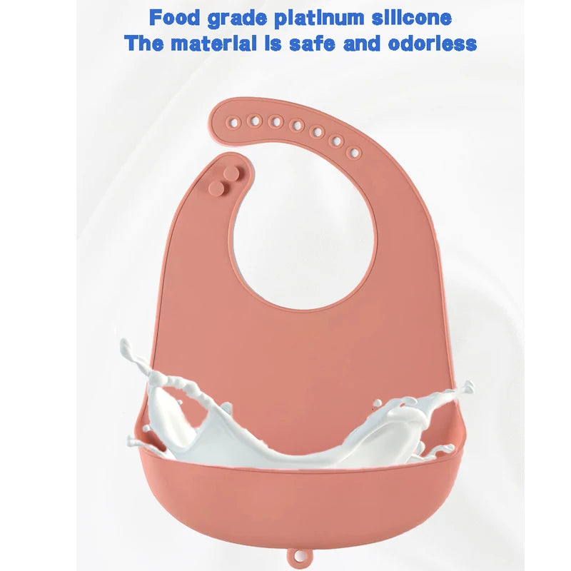 Pink silicone bib with adjustable neck, featuring a pocket to catch spills. Above, text reads "Food grade platinum silicone. The material is safe and odorless."