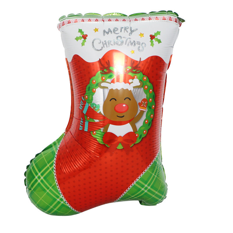 Festive Christmas balloon shaped like a stocking, featuring a smiling reindeer with a red nose inside a green wreath. "Merry Christmas" text and holly decorations adorn the top.