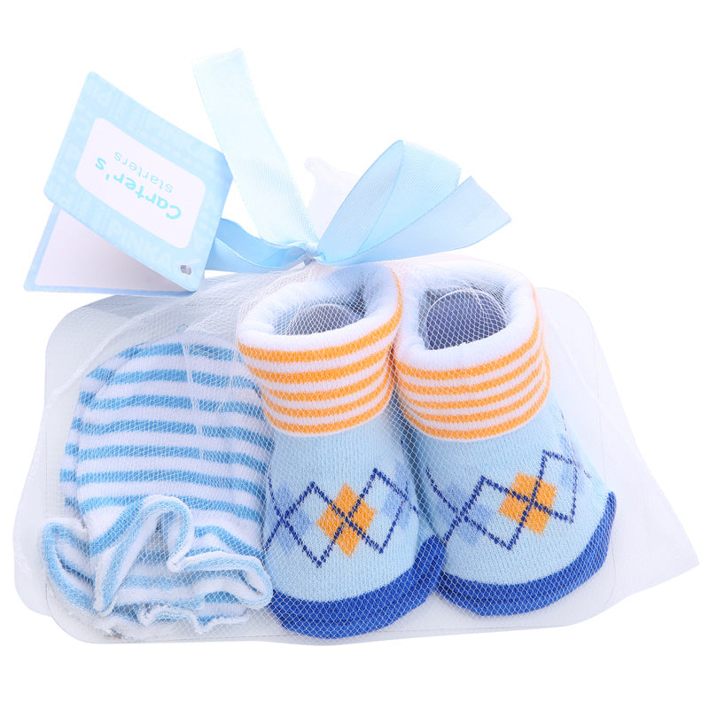 Pack of baby booties and beanie with a blue and orange argyle pattern, wrapped in a net with a blue ribbon and tag. The beanie is blue and white striped.