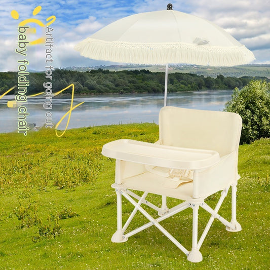 Baby folding chair with a tray and parasol on a grassy field by a lake, under a blue sky. Text on the left reads, “Artifact for going out baby folding chair.”