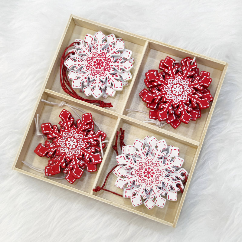 Wooden box with four compartments, each holding intricately designed snowflake ornaments in red and white patterns, on a soft white background.