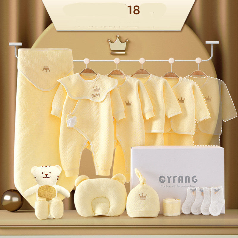 Yellow baby clothing set includes onesies, jackets, a hat, socks, a plush bear, and a boxed pillow, all adorned with a crown motif. Items are neatly displayed on rods and shelves.