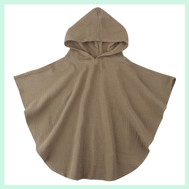 Brown hooded poncho with a loose, flowy design, displayed on a light green background. The poncho has a textured fabric and wide sleeves, providing a relaxed fit.