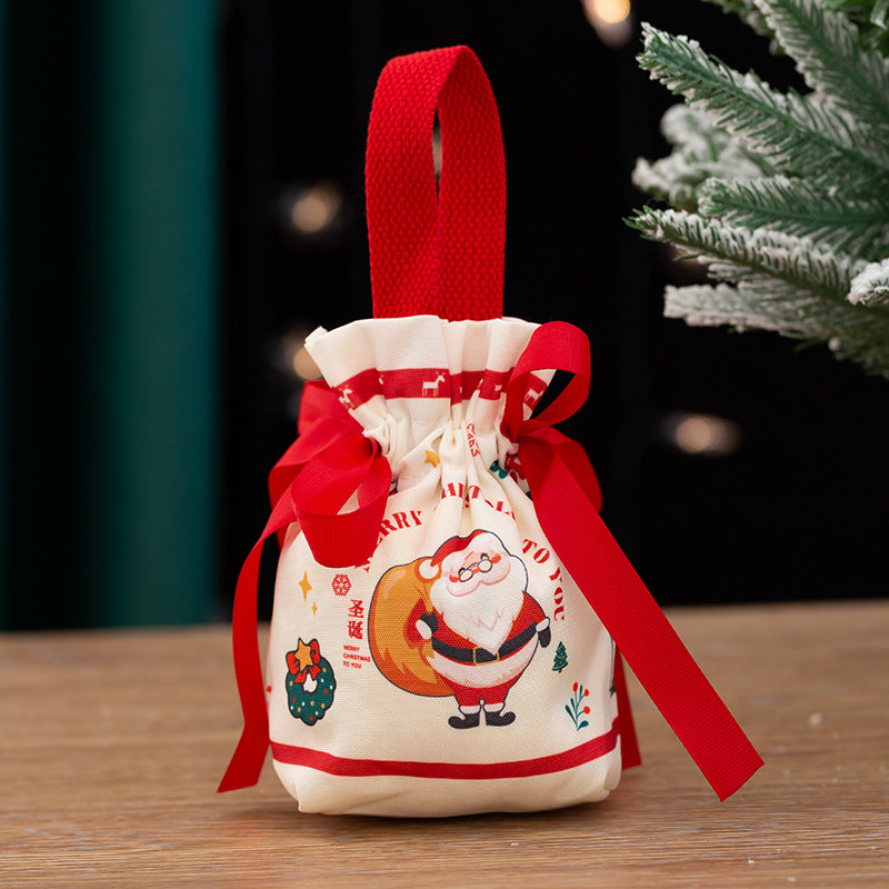 Festive gift bag with a red handle and bow, featuring a cheerful Santa Claus print. It's placed on a wooden surface, with a hint of a Christmas tree in the background.
