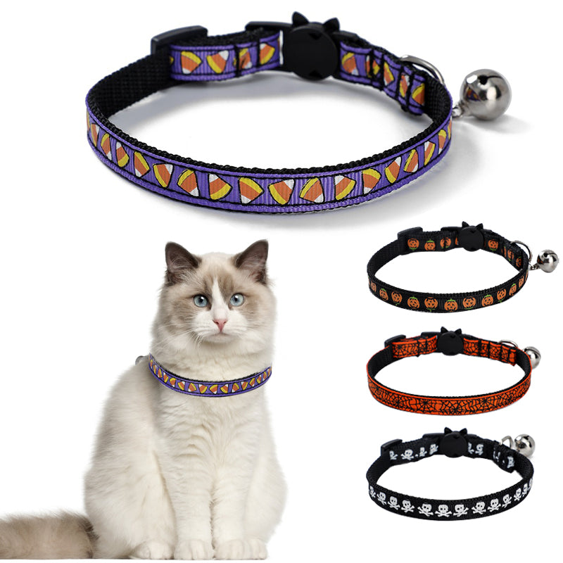 Fluffy cat wearing a purple collar with candy corn design. Additional collars displayed in pumpkin, spider web, and skull patterns, each with a bell.