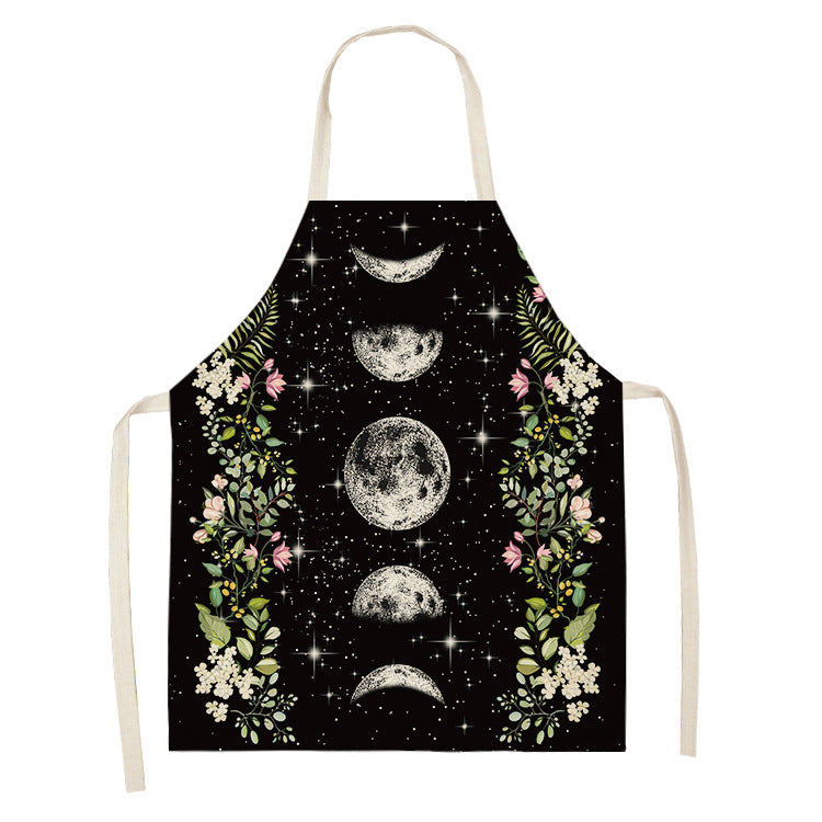 Black apron featuring moon phases and stars with floral borders of pink, white, and green flowers and leaves.