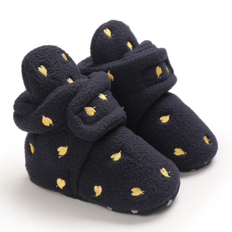 Cozy navy baby booties with a soft texture, adorned with small gold leaf patterns. The booties have a fold-over cuff and adjustable closure for a snug fit.