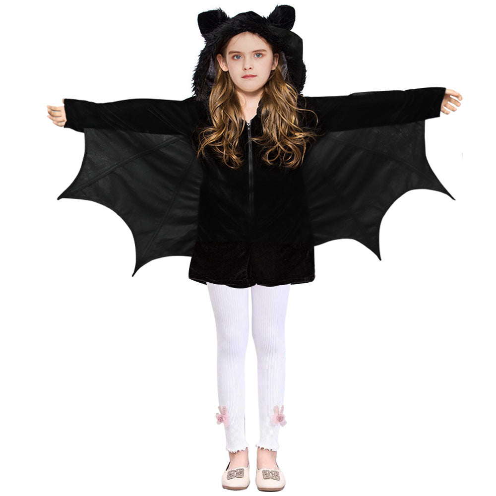 Young girl wearing a black bat costume with wings spread, featuring a hood with ears. She pairs it with white leggings adorned with pink bows and white shoes.