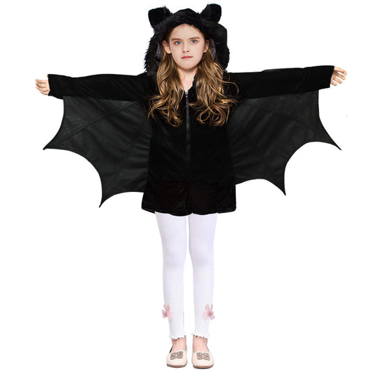 Young girl wearing a black bat costume with wings spread, featuring a hood with ears. She pairs it with white leggings adorned with pink bows and white shoes.