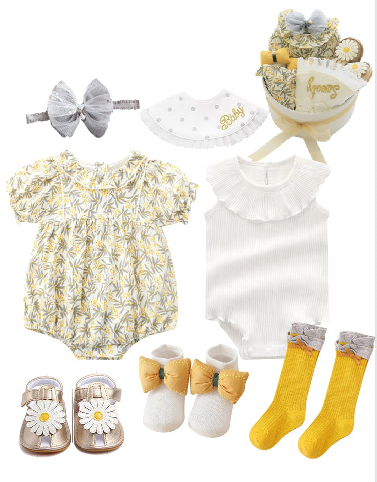 Baby gift set with a floral romper, white ruffled bodysuit, bow headband, bib, yellow socks, bow booties, daisy sandals, and a decorated basket with "happy" inscription.
