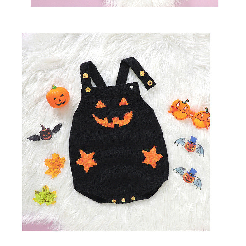 Black knit romper with orange jack-o'-lantern face and stars on a white fur background, surrounded by Halloween-themed items like a pumpkin, bat, leaves, and pumpkin sunglasses.