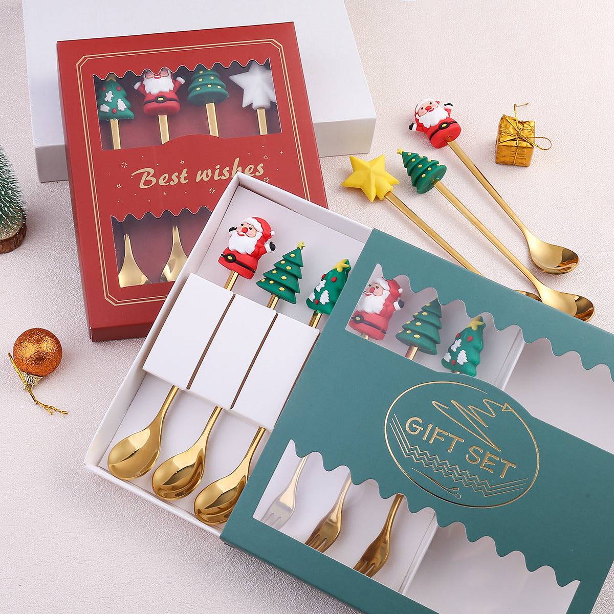 Festive gift sets with gold spoons featuring Santa, Christmas trees, and stars. The boxes, one red and one teal, are decorated with "Best wishes" and "Gift Set" labels.