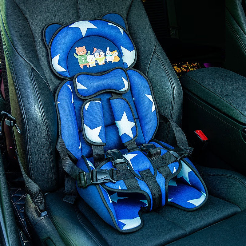 Blue child car seat with white stars and cartoon animals on the headrest, installed in a vehicle on a black leather seat, featuring multiple harness straps for safety.