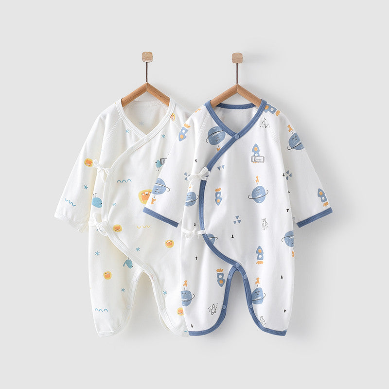 Two infant rompers hang on wooden hangers. One is white with orange and blue planets, the other white with blue trim and space-themed images, including rockets and planets.