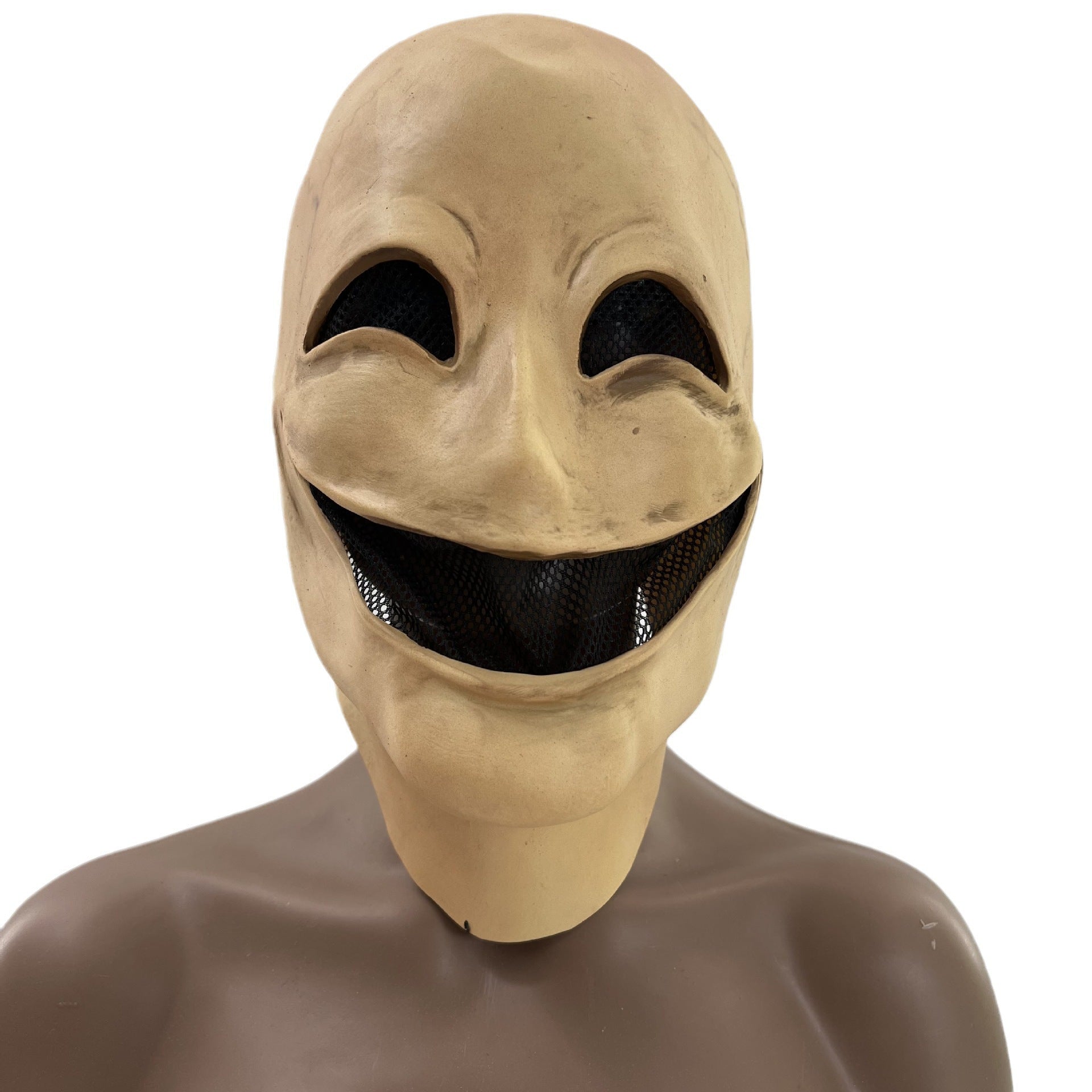 Creepy mask with exaggerated smiling mouth and hollow eyes. The mask is beige with black mesh covering the eye and mouth openings, against a plain background.