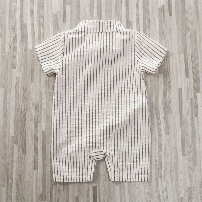 White baby romper with short sleeves and vertical black stripes, shown on a light wood floor. The outfit has a collar and a button-up back, suitable for casual wear.