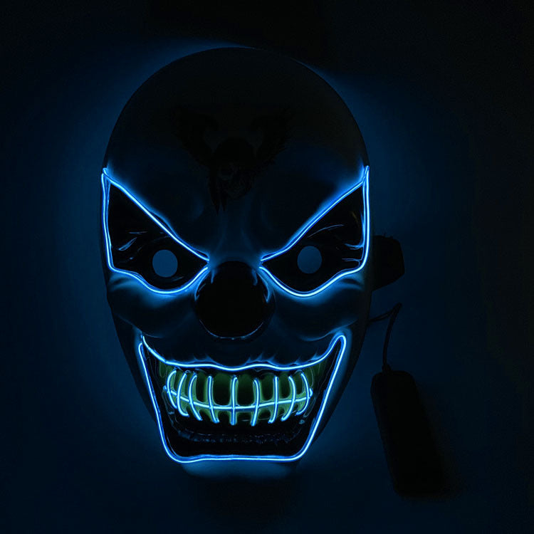 Glowing mask with blue neon outlining fierce eyes and a wide grin with green-lit teeth. The dark background enhances the eerie, intimidating look.