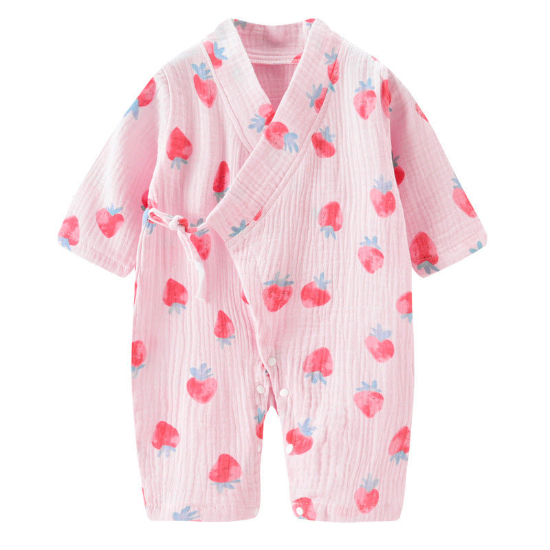 Pink baby romper with a wrap design, adorned with red and blue strawberry patterns. The lightweight fabric has a textured appearance, and features a side tie and buttons.